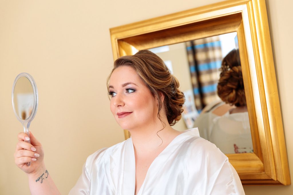 Auch die Braut wirft einen prüfenden Blick in den Spiegel nach dem Brautstyling