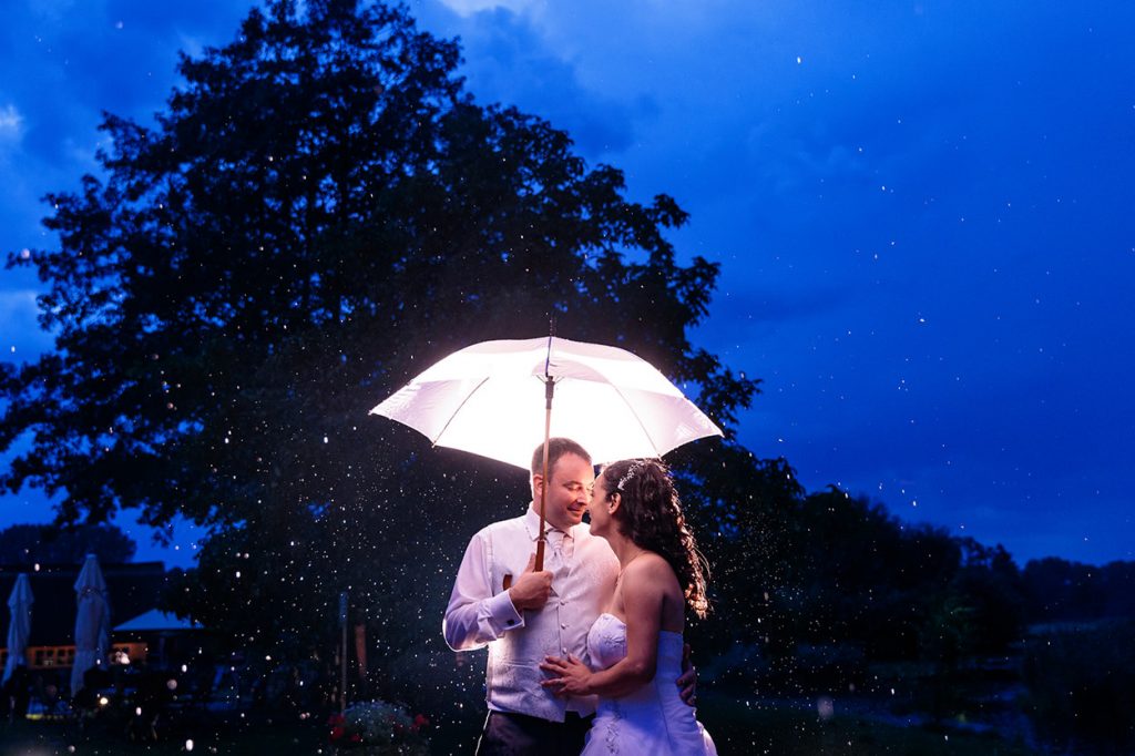 Nur weil es auf der Hochzeit regnet, heißt es nicht, dass die Hochzeitsfotos ins Wasser fallen. Hier ein Brautpaar unter dem Regenschirm zur blauen Stunde im Spreewald