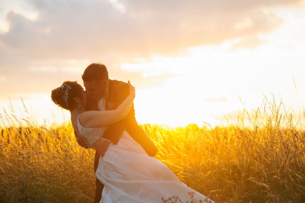 Hochzeitsbilder zur Goldenen Stunde vom Brautpaar im Feld