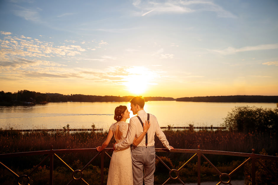 Ein Brautpaar schaut in Hochzeitsbild vom Hochzeitsfotograf verliebt in den Sonnenuntergang über Potsdam und freut sich über das Angebot Ein Brautpaar schaut in Hochzeitsbild vom Hochzeitsfotograf verliebt in den Sonnenuntergang über Potsdam und freut sich über das Angebot
