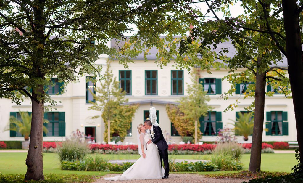 Hochzeitsfoto von Brautpaar im Britzer Garten mit dem Britzer Schloss