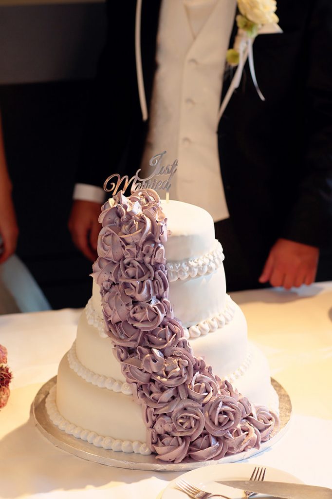 Die Hochzeitstorte mit lila Blumen und einem Just-Married Topping