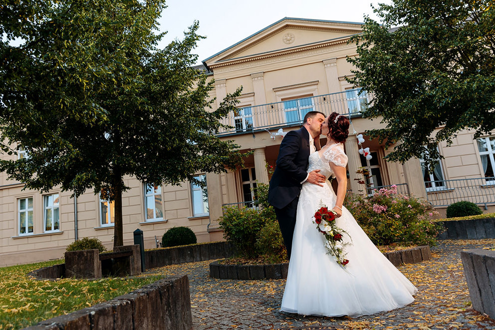 Hochzeitspaar küsst vor Gut Gnewikow am Ruppiner See