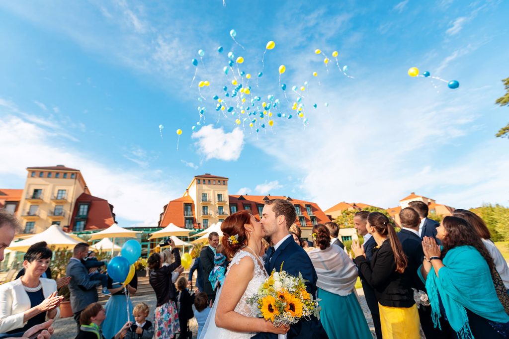 Küssendes Brautpaar unter den fliegenden Luftballons