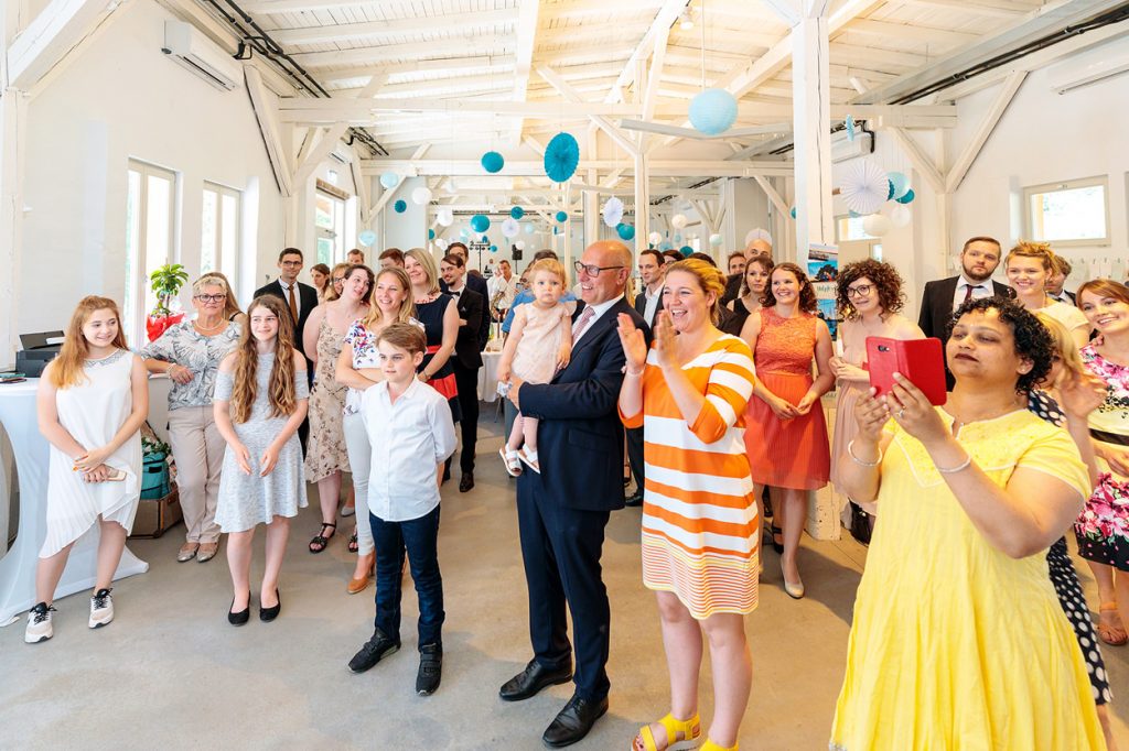 Die Hochzeitsgäste beobachten freudig den Anschnitt der Hochzeitstorte