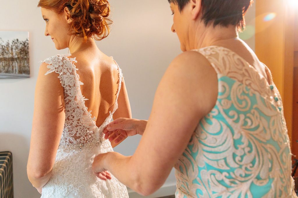 Die Brautmutter macht der Braut das Kleid zu