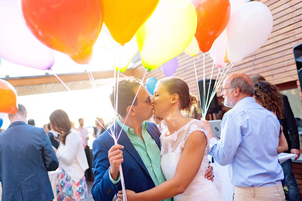 Das Brautpaar mit Luftballons bei der Hochzeitsfeier im Sommer am Yachthafen in Berlin