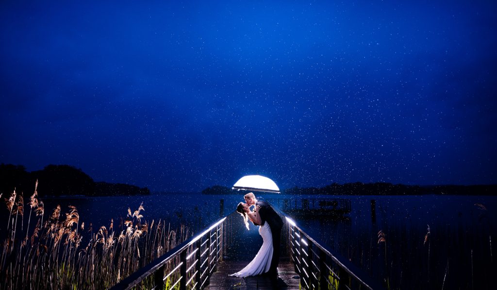 wedding photo of couple in rain at lake in blue hour