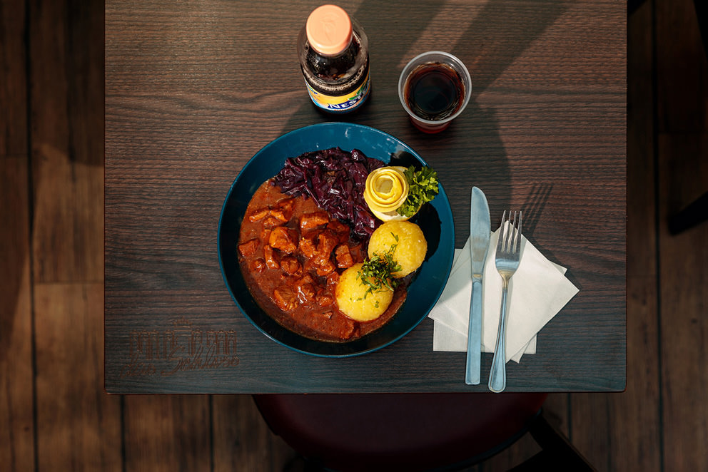 Gulasch mit Klößen und Rotkohl und einem Getränk zum Mittagessen