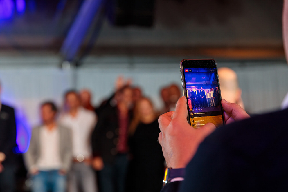 Mann hält Handy in der Hand für Live Aufnahme bei Event