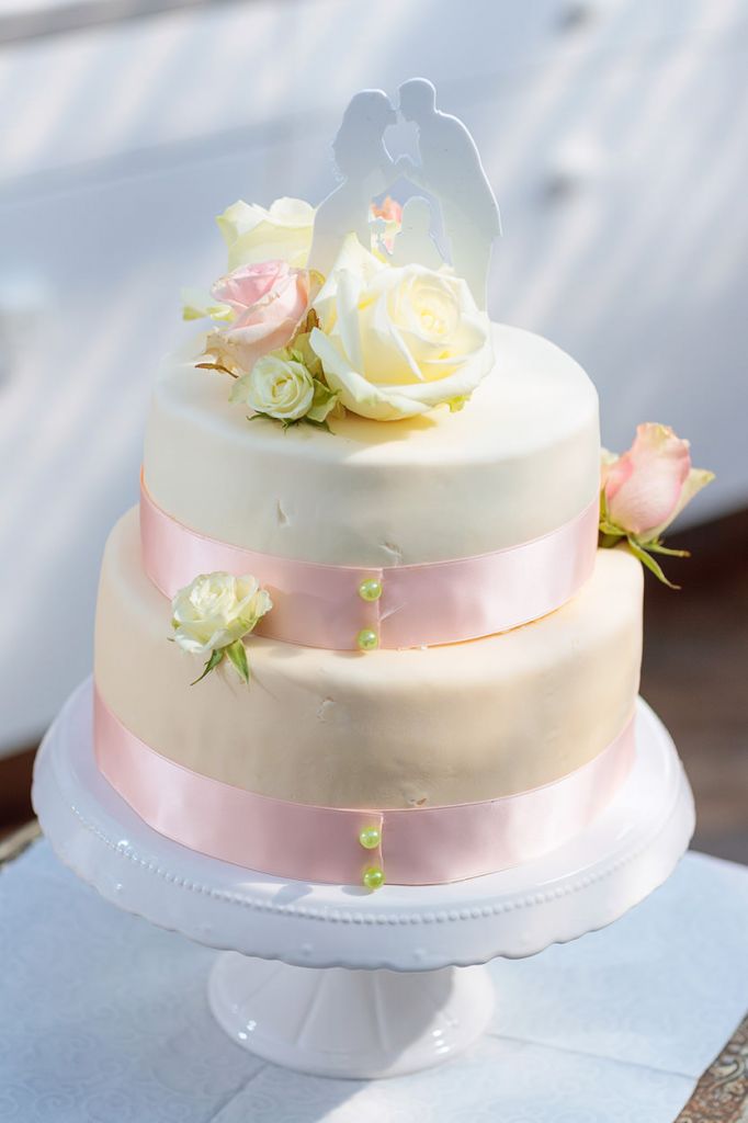 Hochzeitstorte mit Rosen und rosa Band