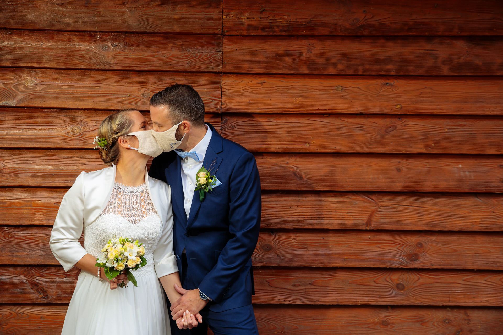 Brautpaar gibt sich mit Maske einen Kuss bei einer Hochzeit im Corona Jahr