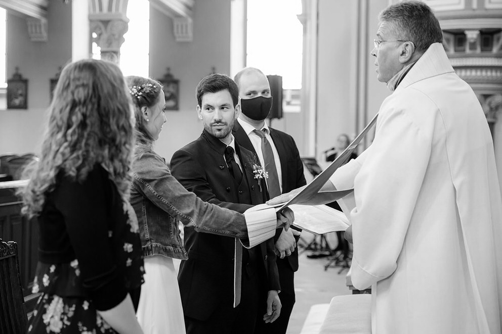 Brautpaar bei kirchlicher Trauung und Trauzeugen mit Maske