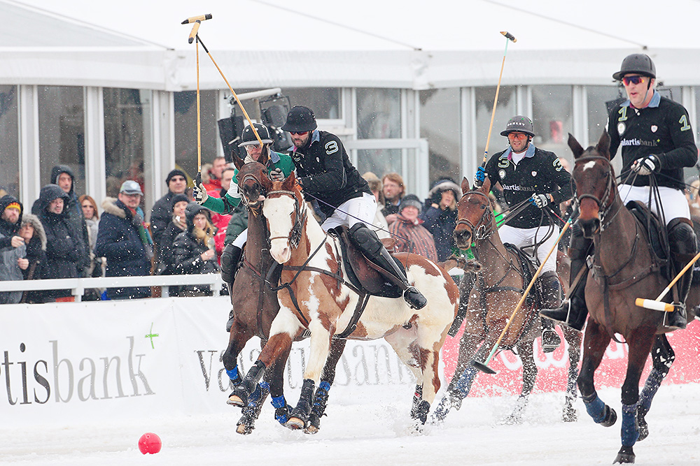 Polo players chasing the red ball during their Snow Polo World Cup match in Kitzbuehel