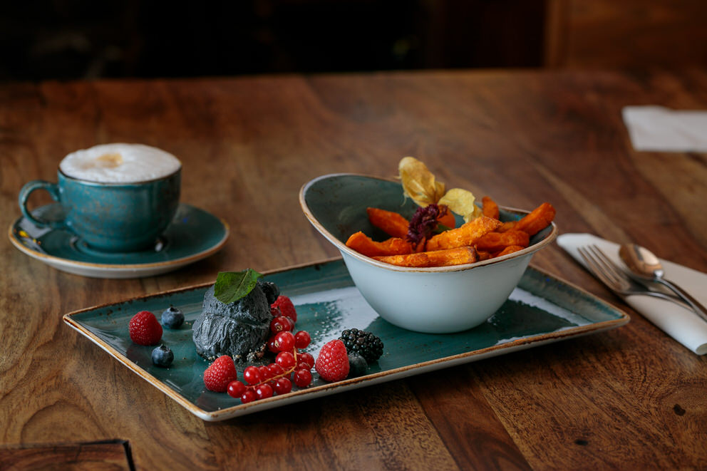 Aufnahme von einem Dessert mit Eis und Früchten. Dazu eine Tasse Kaffee