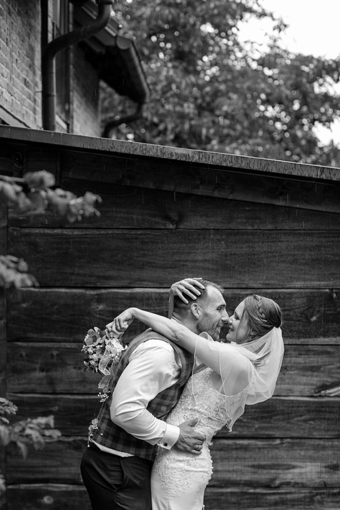 Hochzeitsfotograf im Spreewald fotografiert verliebtes Brautpaar nach der Trauung in schwarz-weiß vor einer Holzwand Hochzeitsfotograf im Spreewald fotografiert verliebtes Brautpaar nach der Trauung in schwarz-weiß vor einer Holzwand
