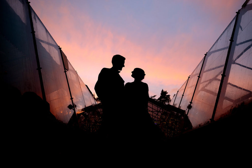 Silhouette eines Brautpaares im bunten Abendlicht nach einem regnerischen Nachmittag Silhouette eines Brautpaares im bunten Abendlicht nach einem regnerischen Nachmittag