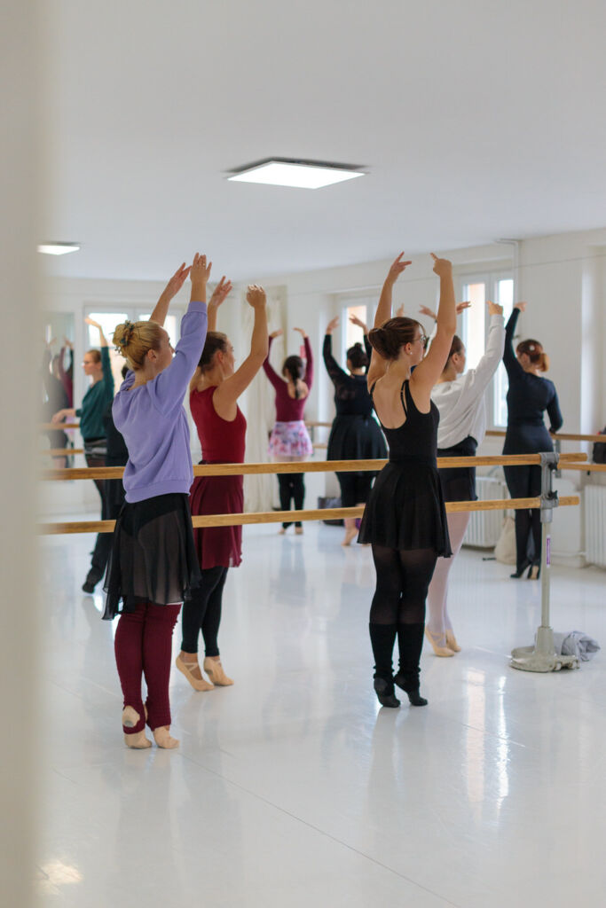 Eine Gruppe von Tänzerinnen übt eine Ballettchoreografie an der Stange in einem hellen Tanzstudio. Die eleganten Bewegungen und die konzentrierte Atmosphäre spiegeln die Leidenschaft und Präzision des Tanzes wider. Perfekt inszeniert für die Social Media Betreuung für Tanzschulen, um die Dynamik und Professionalität des Unterrichts authentisch zu präsentieren.
