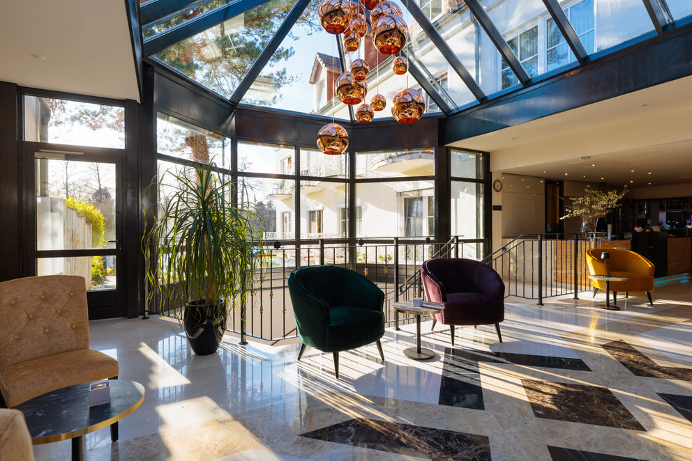 Eine moderne Hotellobby mit großzügigen Glasfronten, die den Raum mit warmem Sonnenlicht durchfluten.