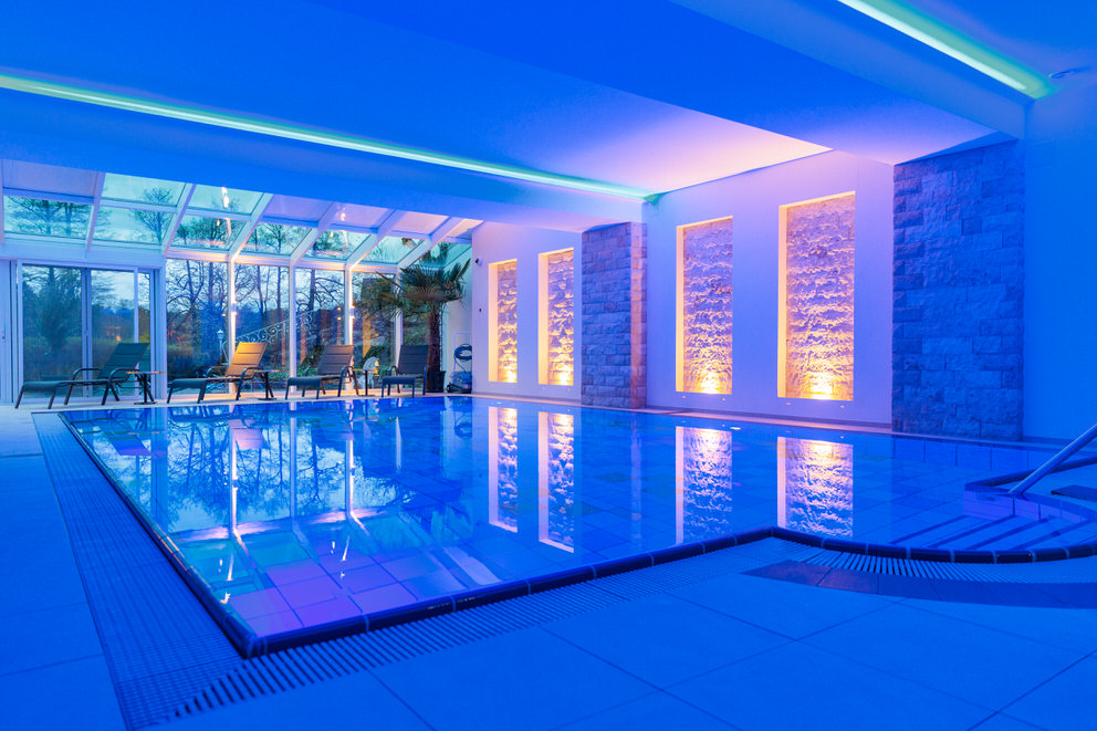 Ein luxuriöser, beleuchteter Innenpool in einem modernen Wellnessbereich.